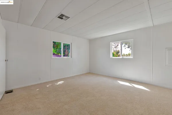 a view of an empty room with chandelier fan and wooden floor