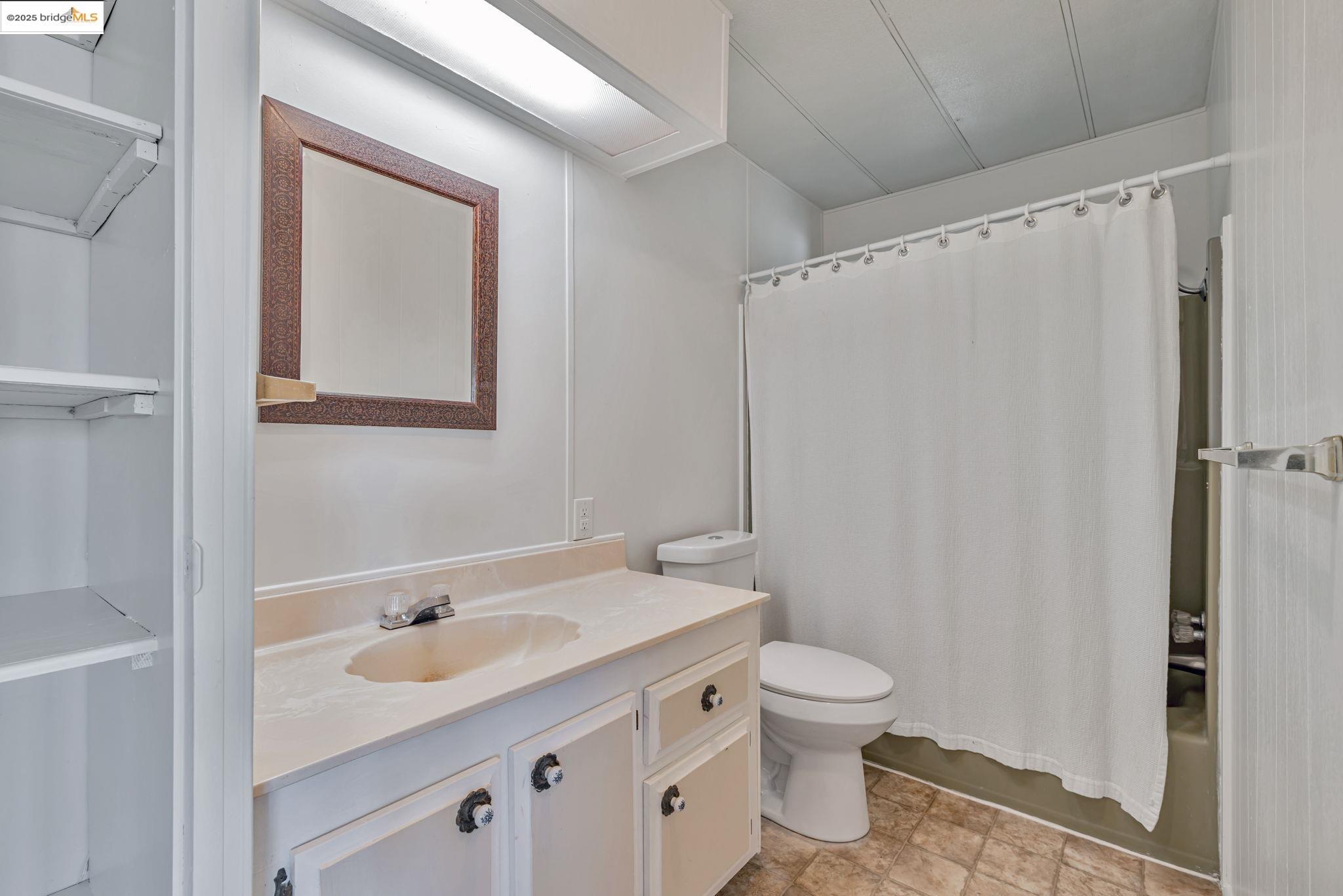 4603 Balfour Road, Unit 58 Brentwood, CA 94513 - Photo 23 of 33 a bathroom with a granite countertop sink toilet a mirror a vanity and shower