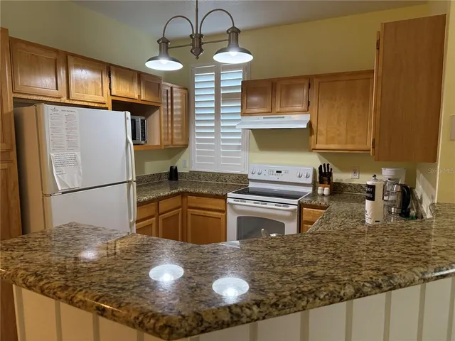 a kitchen with stainless steel appliances granite countertop a sink a refrigerator and a stove