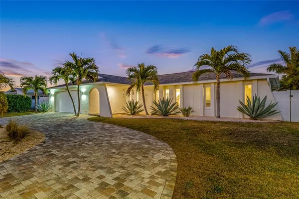 a palm tree sitting in front of a house with a yard
