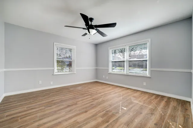 a view of an empty room with a window and wooden floor