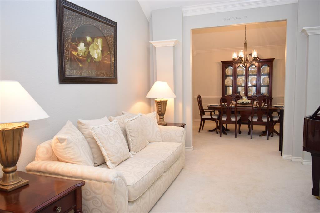 4201 Glistening Spring Rowlett, TX 75088 - Photo 10 of 33 Carpeted living space with a framed art piece and an arched entryway opening to a dining room featuring a dark wood china cabinet and a chandelier