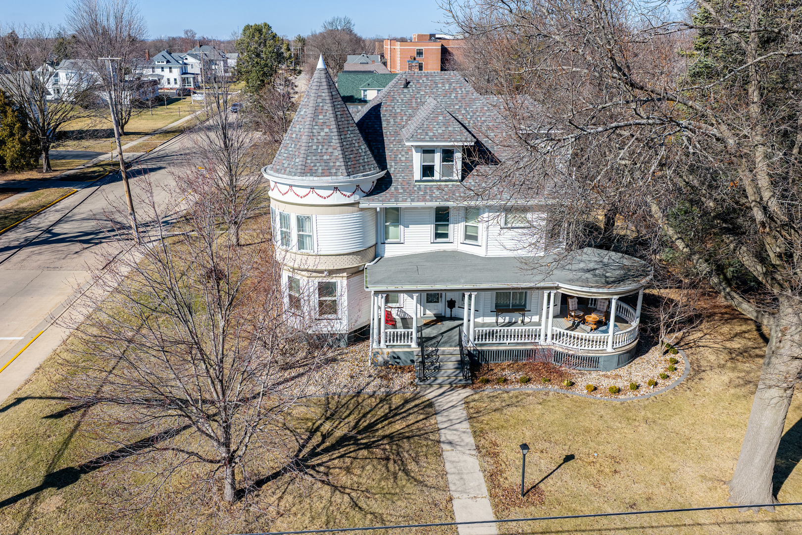 a view of a white house with large tree and wooden fence