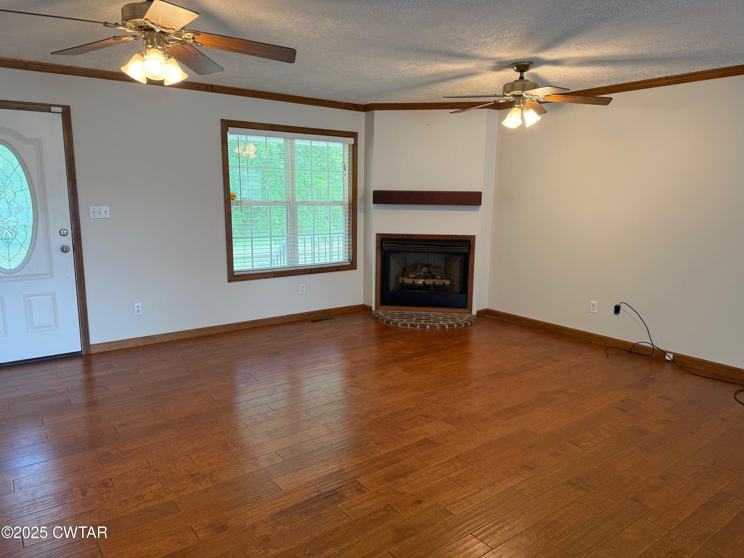 860 Plainview Road Henderson, TN 38340 - Photo 6 of 10 an empty room with wooden floor fireplace and windows