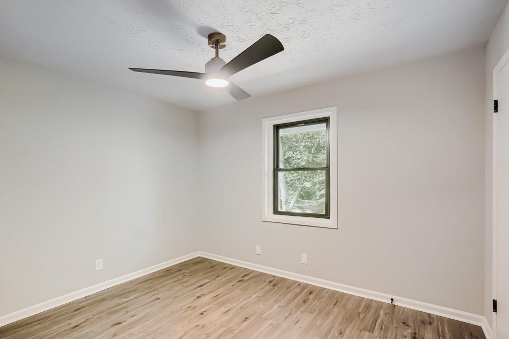 2021 Irwin Bridge Road Northwest Conyers, GA 30012 - Photo 32 of 43 an empty room with wooden floor ceiling fan and windows