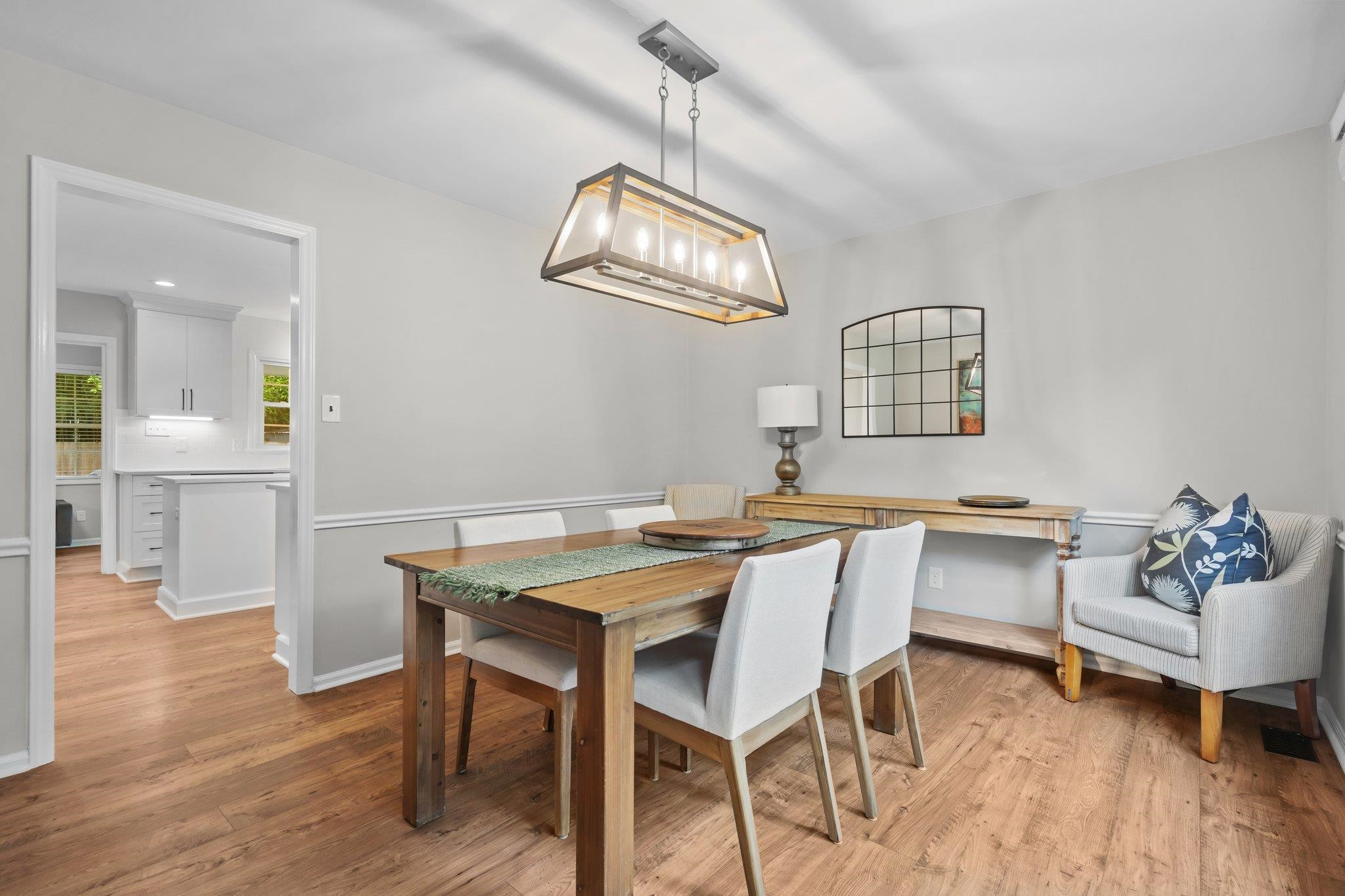 5209 Cedarwood Drive Raleigh, NC 27609 - Photo 5 of 33 a dining room with wooden floor a chandelier a wooden table and chairs