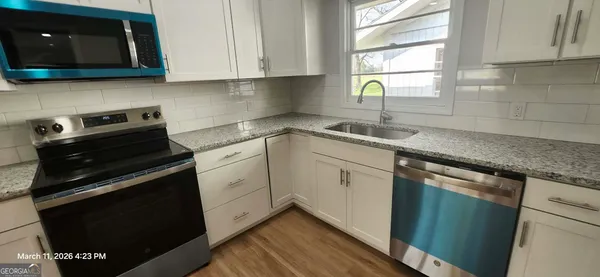 a kitchen with granite countertop white cabinets stainless steel appliances and a sink