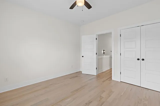 an empty room with chandelier fan and windows