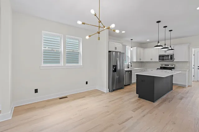 a kitchen with stainless steel appliances kitchen island granite countertop a refrigerator a sink dishwasher a stove and a refrigerator