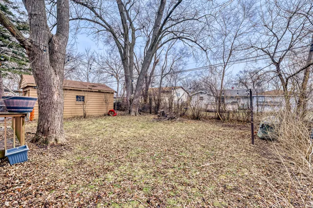 a backyard of a house with large trees and wooden fence