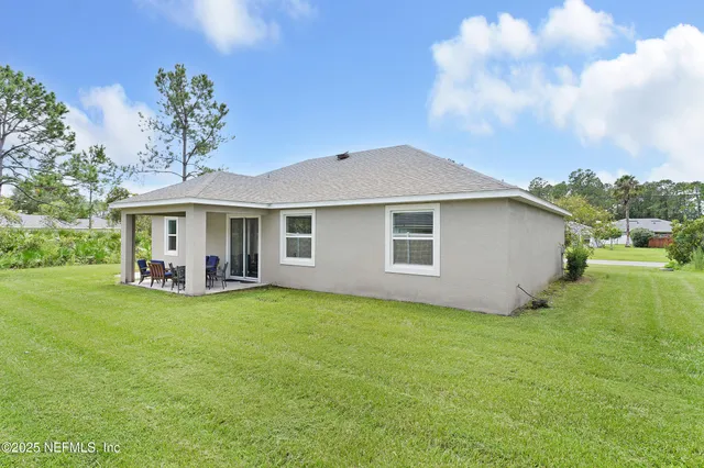 a view of a house with backyard and a tree