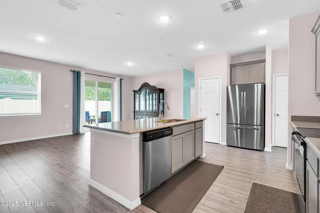 a kitchen with stainless steel appliances granite countertop a refrigerator a stove a sink and a large window