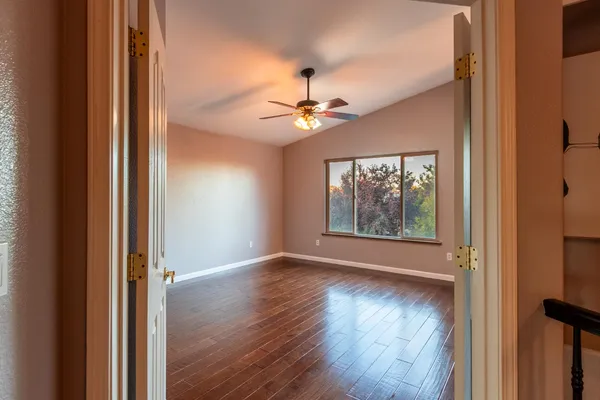 a view of an empty room with wooden floor and a window