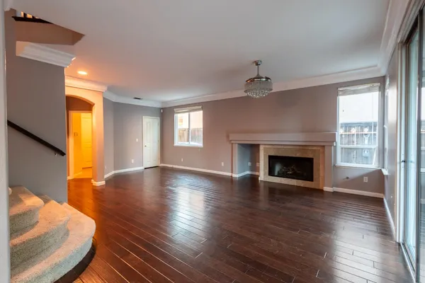 an empty room with wooden floor fireplace and windows