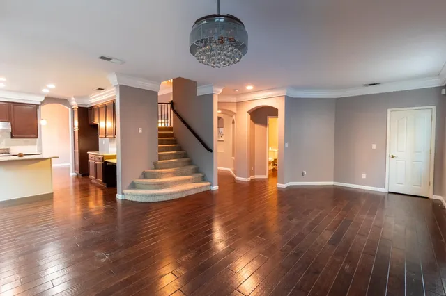 a view of a room with wooden floor staircase and a kitchen