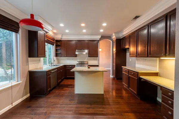 a large kitchen with stainless steel appliances kitchen island granite countertop wooden cabinets a sink and dishwasher