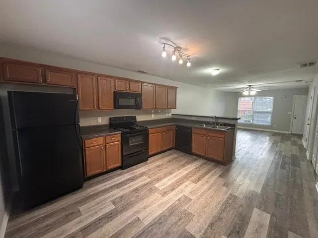 a kitchen with stainless steel appliances kitchen island granite countertop a refrigerator a sink dishwasher a stove and a microwave oven on granite countertops