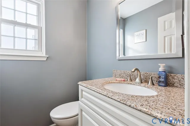 a bathroom with a granite countertop sink mirror vanity and toilet
