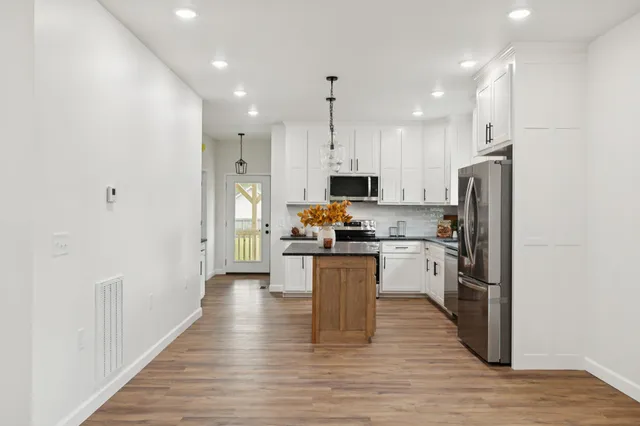 a kitchen with stainless steel appliances granite countertop a refrigerator a stove top oven a sink and dishwasher with wooden floor