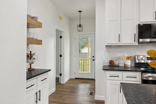 an empty room with wooden floor ceiling fan and windows