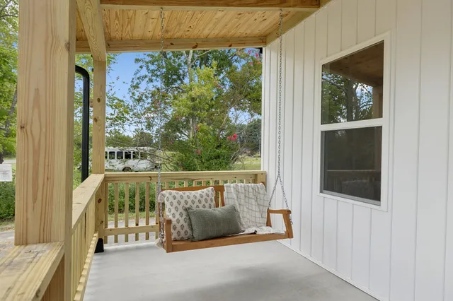 an empty room with wooden floor and a kitchen