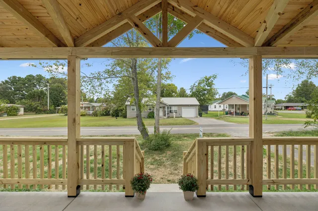 an empty room with wooden floor kitchen view and a window