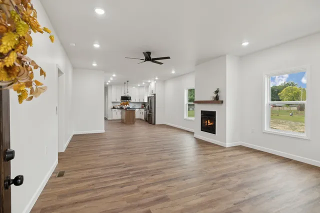 an empty room with wooden floor kitchen view and a window