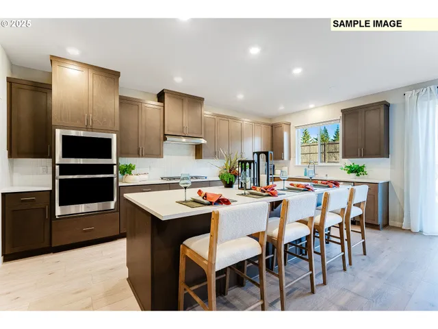 a kitchen with stainless steel appliances kitchen island granite countertop a dining table chairs and refrigerator