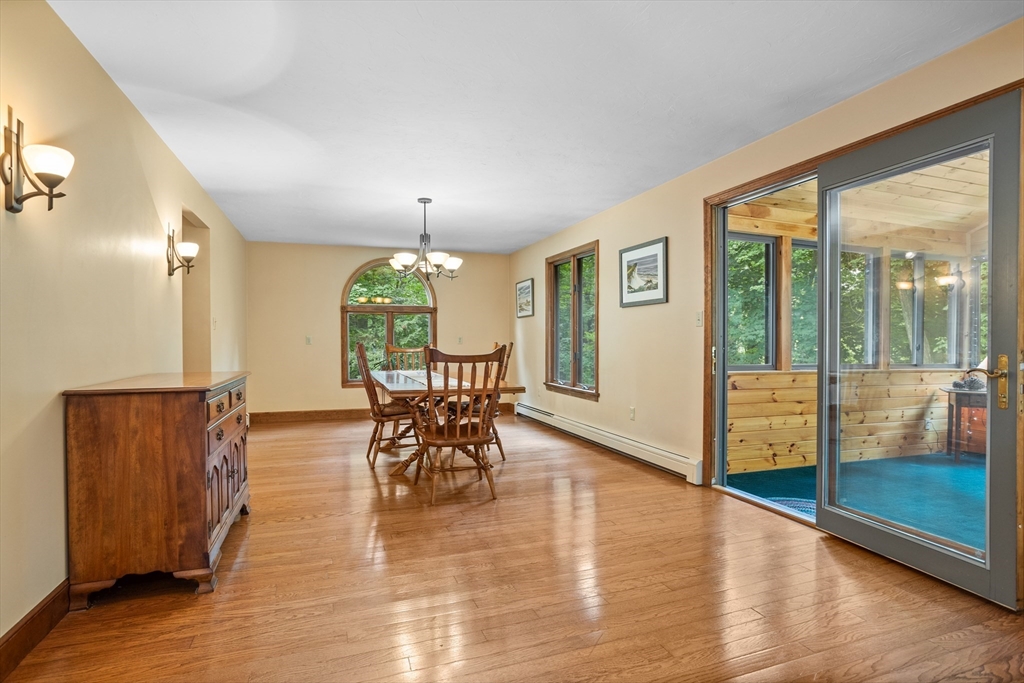 773 Great Road Stow, MA 01775 - Photo 8 of 37 a dining room with wooden floor a chandelier a glass table and chairs
