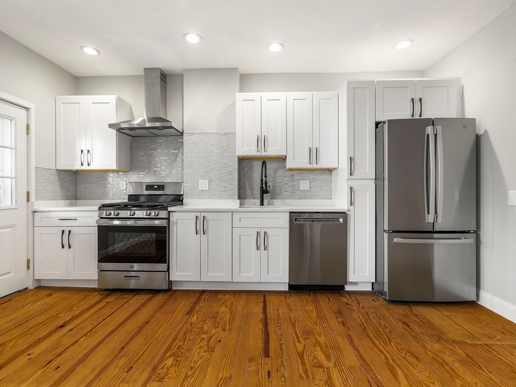 131 A Cottage Street, Unit 2A Boston, MA 02128 - Photo 2 of 16 a kitchen with cabinets stainless steel appliances and wooden floor