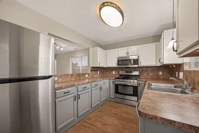 a kitchen with stainless steel appliances granite countertop a stove a sink dishwasher a refrigerator and a microwave