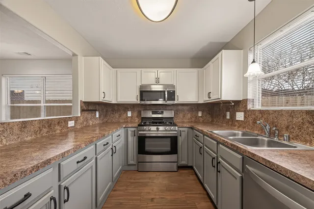a kitchen with granite countertop a sink stainless steel appliances and cabinets