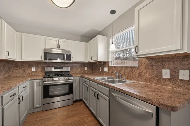 a kitchen with stainless steel appliances granite countertop a sink a stove and cabinets