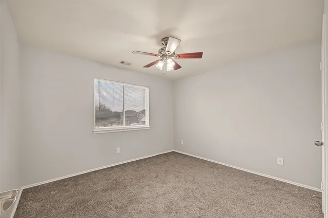 an empty room with a window and a fan
