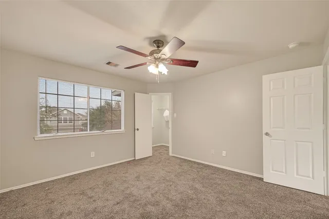 an empty room with windows and fan