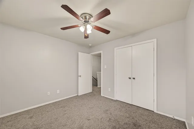 an empty room with chandelier fan and windows