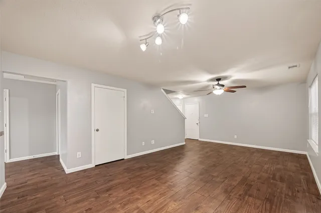 an empty room with wooden floor fan and window