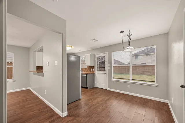 a view of empty room with wooden floor and window