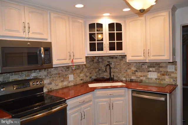 a kitchen with stainless steel appliances granite countertop a sink stove and cabinets