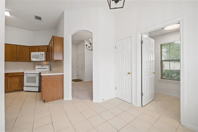 a view of a kitchen with a sink and dishwasher a refrigerator with white cabinets