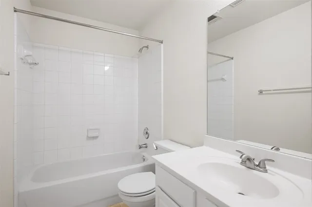 a bathroom with a bathtub shower sink vanity mirror and toilet