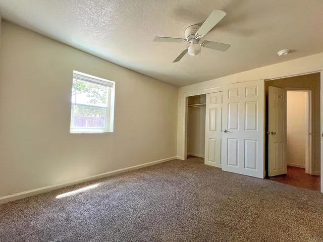 an empty room with a window and a fan