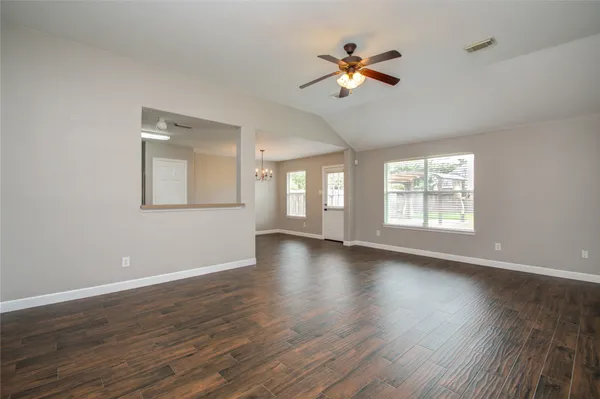 a view of an empty room with wooden floor and a window