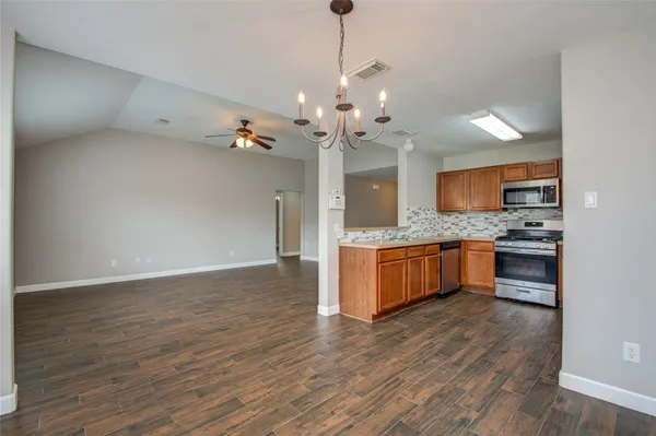 a large kitchen with a sink and dishwasher a stove with wooden floor