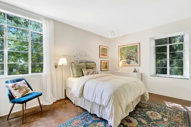 a bedroom with a bed a large window with outer view and chair