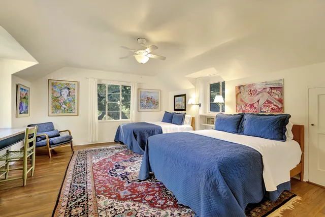 a bedroom with a large bed a rug and two windows