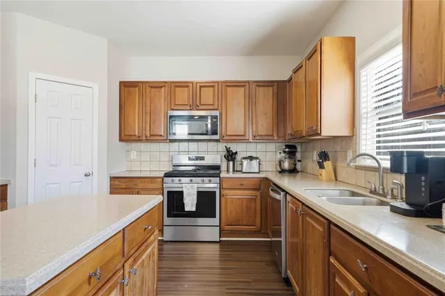 a kitchen with stainless steel appliances granite countertop a sink a stove cabinets and a counter space
