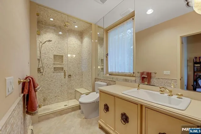 a bathroom with a double vanity sink a toilet a mirror and shower