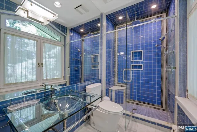 a bathroom with a sink a toilet a mirror and shower
