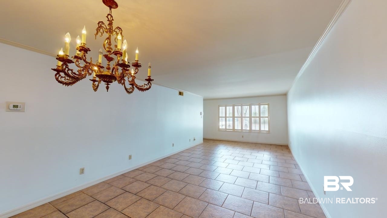 4009 Old Shell Road, Unit C13 Mobile, AL 36608 - Photo 8 of 32 Spare room featuring crown molding, a chandelier, baseboards, and light tile patterned flooring